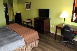 基林Scottish Inns Killeen near Fort Cavazos的酒店客房配有一张床和一张书桌及一台电视