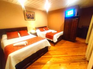 昆卡Hotel Calle Angosta的酒店客房设有两张床和电视。