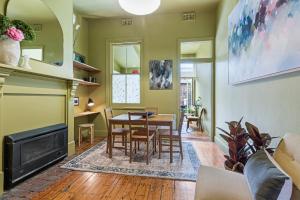 墨尔本Colourful & Charming 2-Bed Fitzroy Heritage Home的客厅配有桌子和壁炉