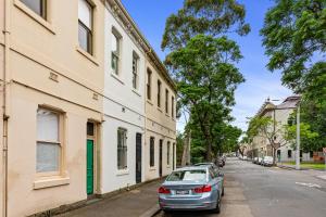 墨尔本Colourful & Charming 2-Bed Fitzroy Heritage Home的停在街道上建筑物旁边的汽车