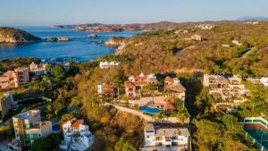 圣克鲁斯华特库Casa Ceiba Huatulco - Adults Only的水边山丘上房屋的空中景观