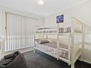 穆尔瓦拉3 Anglers Close的卧室配有白色双层床和窗户。