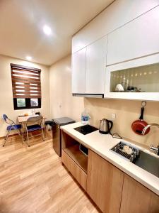 海防HPT Home II Apartment - Homestay chuỗi căn hộ Hải Phòng的厨房配有白色橱柜和桌子