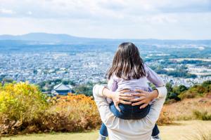 奈良ANDO HOTEL NARA Wakakusayama -DLIGHT LIFE & HOTELS-的把孩子抱在山顶的人
