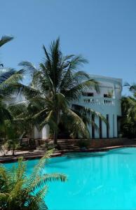 马林迪Mwezi Nyota的一座棕榈树环绕的建筑,位于游泳池前