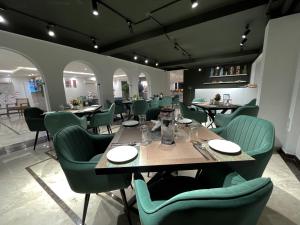 古尔冈AVA Hotels and Corporates Millennium City的用餐室配有桌子和绿色椅子