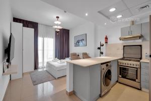 迪拜Sleek Studio - Red Residence-L8 - Near ISD Stadium的厨房以及带炉灶和洗碗机的客厅。