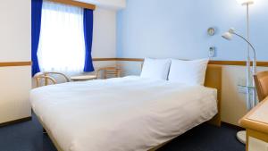 鹿儿岛Toyoko Inn Kagoshima chuo eki Higashi guchi的卧室设有一张白色大床和一扇窗户。