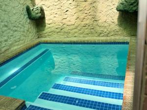 贝拉贝拉Dula Monate Holiday Flats的一座拥有蓝色瓷砖的石墙游泳池