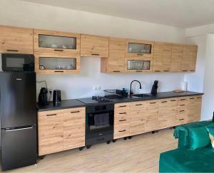 新塔尔格Apartament Guziczek2的厨房配有木制橱柜和黑色冰箱。