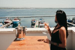 塔兰托A-mare Exclusive Rooms & Suites的坐在阳台上的桌子旁的一位妇女,她享有海港的景色