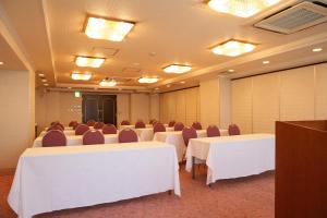 川崎柯丽格亚广场酒店的一间会议室,配有白色的桌椅和灯光