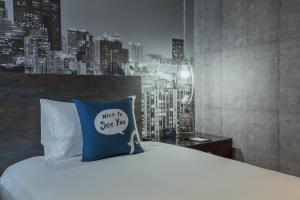 高雄西悠巢旅-高雄车站馆的一张带蓝色枕头的床,上面有标志