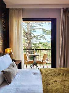 卢马罕Hotel Bastide & SPA - Villa de Lourmarin的一间卧室配有一张床,阳台配有桌子