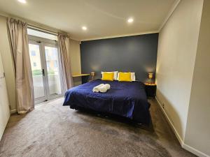 惠灵顿Executive, Spacious & Modern Home, 8 Beds!的一间卧室配有蓝色的床和黄色枕头