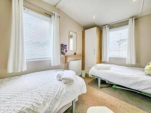 佩文西Escape to Paradise at Pevensey Bay Holiday Park 13 Woodland Walk的一间卧室设有两张床和两个窗户。