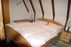 希格斯多夫Ferienhaus Bergwiese的一张带木制框架和白色床单的床
