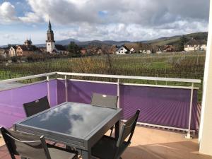 GertwillerDomaine Rosfelder - locations de gîte et cabane insolite的阳台配有一张桌子和椅子,阳台设有紫色的围栏