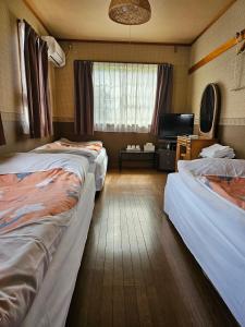 Shimo-taga枇杷物語的酒店客房设有两张床和电视。