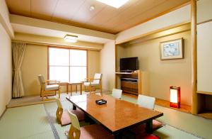 汤泽町汤泽新大谷日式旅馆的客厅配有桌椅和电视。