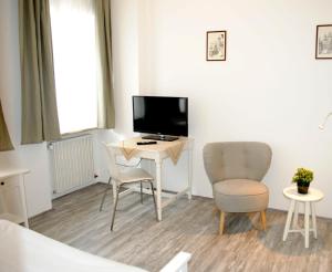 罗滕堡Hocher Hotel的客房设有一张桌子、一台电视和两把椅子