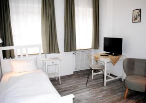 罗滕堡Hocher Hotel的一间卧室配有一张床和一张书桌及电视