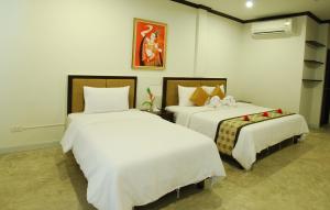 卡马拉海滩普卡玛拉套房式酒店的一间卧室配有两张带白色床单的床