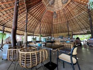 哈林海滩The Sea Resort Haad Rin的一间设有桌子和椅子的稻草屋顶餐厅