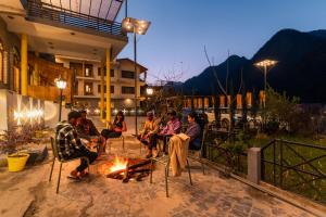 卡索尔The Hosteller Kasol, Parvati Valley的一群人晚上坐在火炉旁