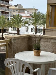 萨洛Apartamentos Amatista的棕榈树阳台的白色桌椅