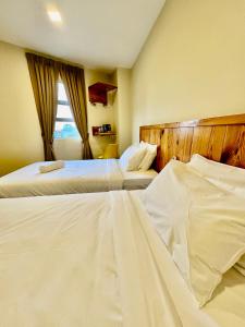 莎阿南Swing & Pillows - Apple Hotel Shah Alam的酒店客房设有两张床和窗户。