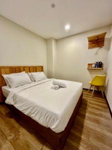 莎阿南Swing & Pillows - Apple Hotel Shah Alam的一间卧室配有一张床和一张黄色椅子