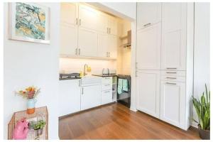 伦敦Stylish, 2 Bed Apartment, Muswell Hill的厨房铺有木地板,配有白色橱柜。