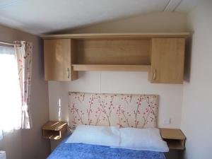 英戈尔德梅尔斯Seaview Ingoldmells Bromley 10 Berth 4 Bedrooms Central heated的一间卧室配有一张带蓝色床罩和木制橱柜的床。