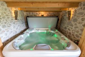 班斯卡比斯特里察La Ferme Francej Luxury Farmhouse Bohinj的石墙客房内的按摩浴缸