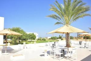 特里法TMK Marine Beach - All Inclusive Seafront resort的一个带椅子和遮阳伞的庭院和棕榈树