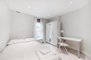 伦敦Modern 3 Bed Apartment in Hampstead的白色卧室配有床和书桌