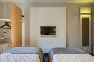 因达亚图巴Rio hotel by Bourbon Indaiatuba Viracopos的客房设有两张床和一台墙上的电视。
