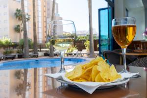 甘迪亚西贝莱斯海滩酒店的一张桌子,上面放着两杯葡萄酒和薯条