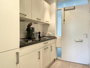吕贝克Strand Suite的白色的厨房,配有白色的橱柜和门