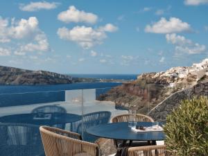 伊亚Olvos Luxury Suites的海景阳台上的桌椅