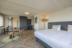 艾默伊登Leonardo Hotel IJmuiden Seaport Beach的酒店客房设有一张大床和一张桌子。