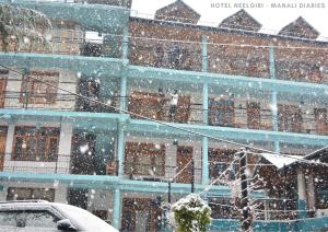 马拉里Hotel Neelgiri - Manali Diaries的一座雪落在前面的建筑