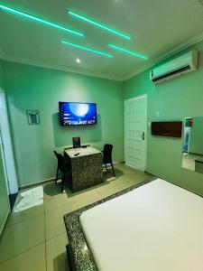 马瑙斯Pousada Ponta Negra的卧室配有桌子和墙上的电视。