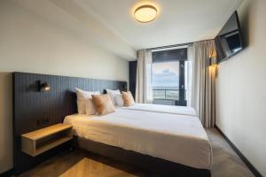 艾默伊登Leonardo Hotel IJmuiden Seaport Beach的一间卧室设有一张大床和窗户