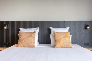 艾默伊登Leonardo Hotel IJmuiden Seaport Beach的一间卧室配有带橙色和白色枕头的床