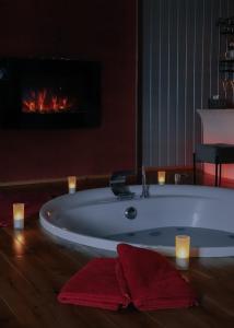 特镇L'Eden - Suite privative avec jacuzzi et sauna的带浴缸的浴室,配有壁炉