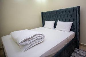 KerichoTegera Homes的一张带黑色床头板、白色床单和枕头的床