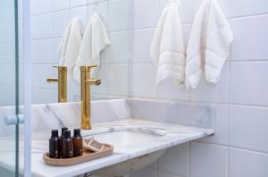 巴拉-沙希Casa Hotel Sahy的白色瓷砖浴室设有水槽和毛巾