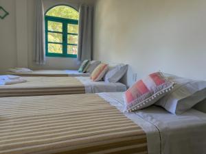 阿拉亚尔达茹达Vila Rita Hostel Arraial d'Ajuda的窗户房间里三张床的组合